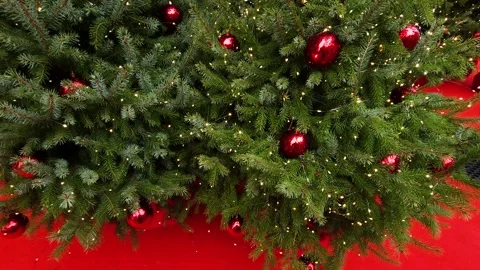 Christmas tree with dark red balls and flashing garland on a red background Stock Footage 323510089