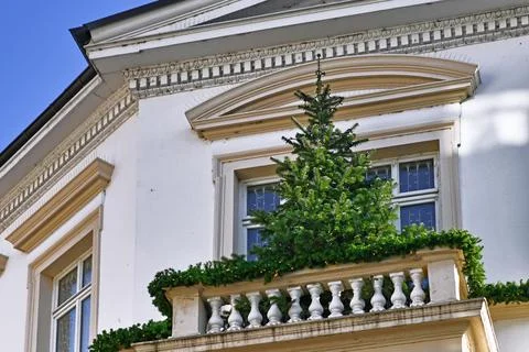 Christmas tree decorated with light chain standing on balcony of old historic Stockfoto's
