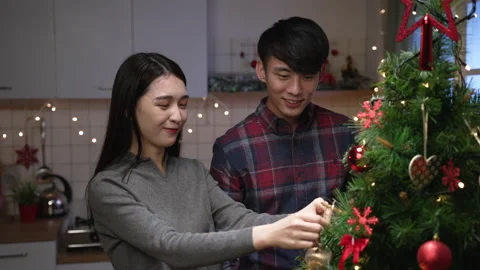 Christmas tree decorating couple putting on balls Stock Footage 165755073