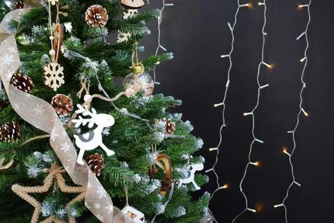 Christmas tree with decorations in a rustic style and garlands on a dark back Stock Photos