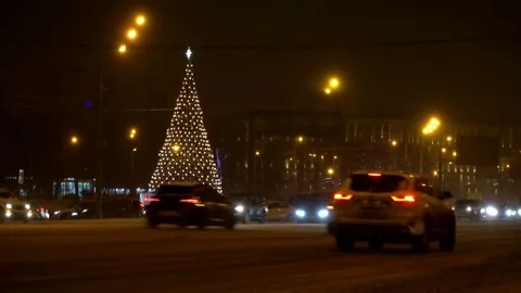 Christmas tree glows brightly in night city winter snow-covered road amid Stock Footage 84331880