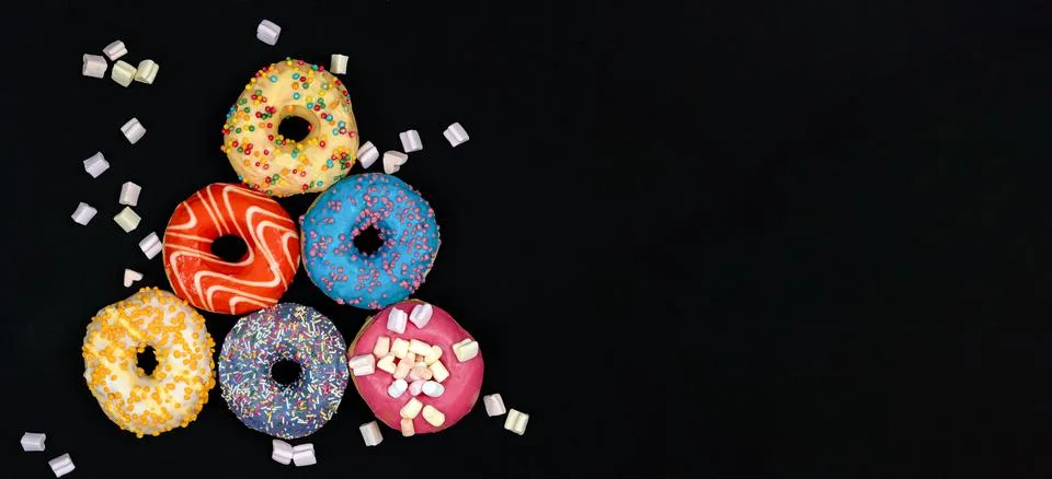 Christmas tree made of multi-colored donuts on a black background. Stock Photos
