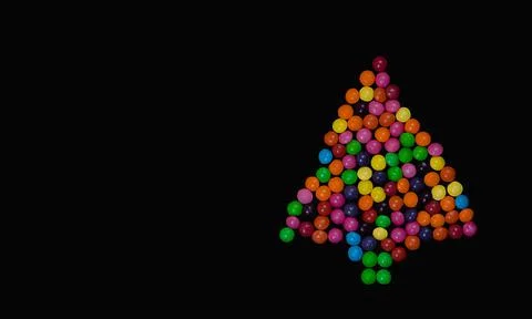 Christmas tree made of multi-colored dragees on a black background. Stock Photos