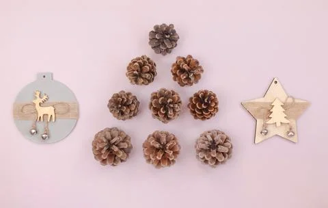 Christmas tree made of pine cones and wooden decorations on pastel pink Stock Photos