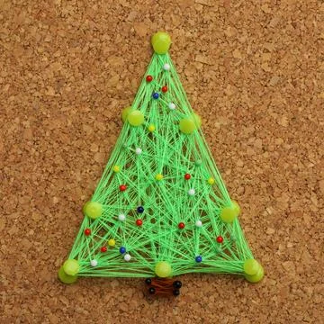 Christmas tree made of thread and pins on cork board. String art Stockfoto's