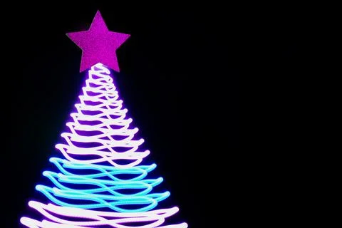 Christmas tree in neon rays on black. Creative Xmas pattern. Stock Photos
