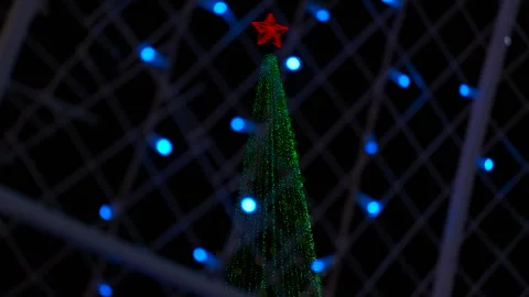 Christmas tree with red star topper seen through decorative lights 스톡 동영상 334785406