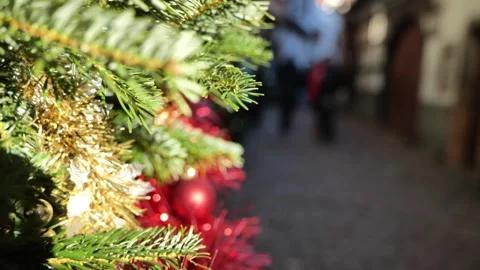 A Christmas tree with red tinsel and ornaments, and passing pedestrian Stock Footage 340516165