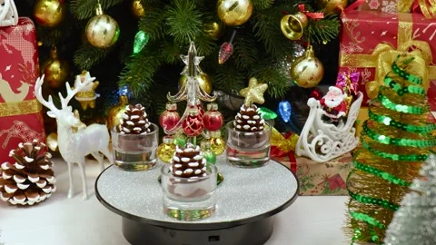 A Christmas tree rotates on a stand surrounded by pine cones Video stock 260878493