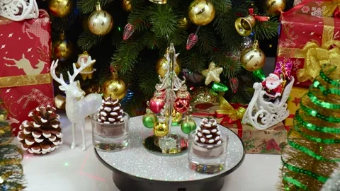 A Christmas tree rotates on a stand, surrounded by pine cone-shaped candles Stock Footage 260878585