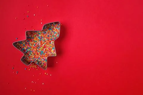 Christmas tree shape cookie cutter filled with colorful sugar sprinkles Stock Photos