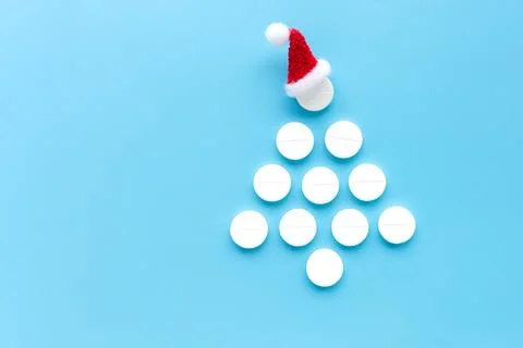Christmas tree shape made of white pills with a Santa hat on top on a blue .. Stock Photos