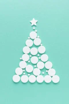 Christmas tree shape made of white pills with star on top, green background.. Stock Photos