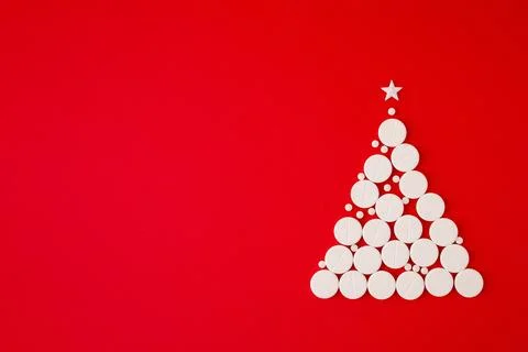 Christmas tree shape made of white pills with a star on top on a red backgr.. Stock Photos