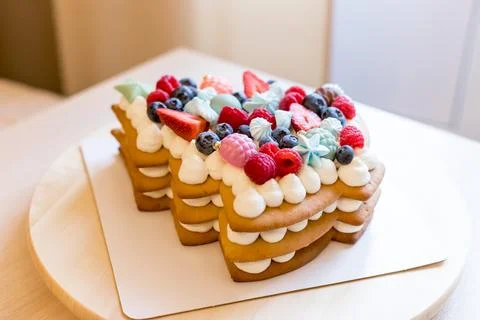 The christmas tree-shaped layer cake is decorated with fresh berries, chocolate Stock Photos