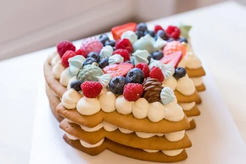 The christmas tree-shaped layer cake is decorated with fresh berries, chocolate Stock Photos