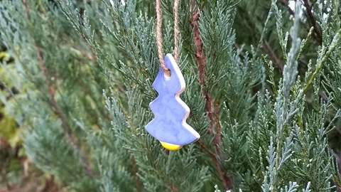 Christmas tree toy in shape of a spruce tree decorates branches of thuja Stock Footage 256883035