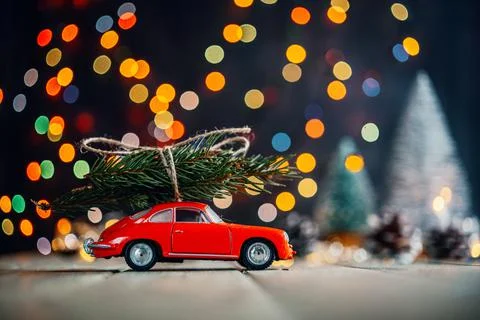 Christmas trees delivery background, red toy car with fir tree against colorful Stock Photos