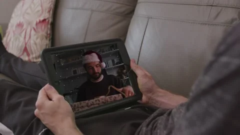 Christmas videocall laying on a sofa, opening a christmas present Stock Footage 145425248