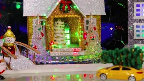 In a Christmas village, a yellow car pulls up to two decorated houses 動画素材 346149003
