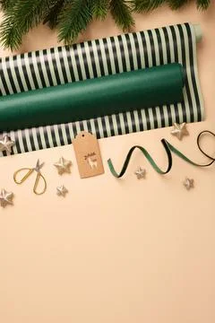 Christmas wrapping paper rolls, brown gift tag, and gold stars on beige backg Foto stock