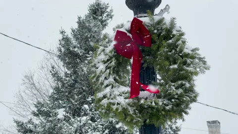 Christmas Wreath on light-post is covered in snow during a blizzard Video stock 145293610