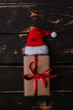 Christmass flatlay gift box and Santa hat on wooden background. Stock Photos