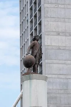 Christopher Columbus statue with globe in front of modern concrete building Stock Photos