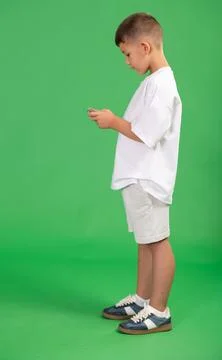 Chroma key compositing. Boy in white clothes scrolling through smartphone screen 스톡 사진