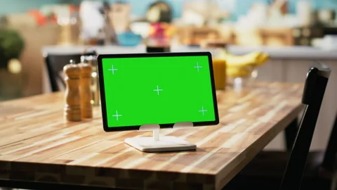 Chroma key display on tablet placed on dining table in rustic empty kitchen Stock Footage 323331396