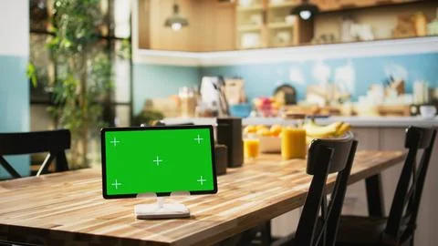 Chroma key display on tablet placed on dining table in rustic empty kitchen Stock Photos