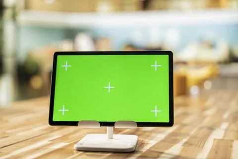 Chroma key display on tablet placed on dining table in rustic empty kitchen Stock Photos
