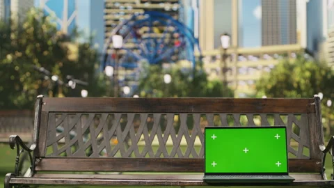Chroma key editable screen on laptop in urban park with skyscrapers Stock Footage 343507574