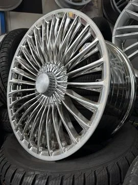 Chrome alloy wheel on tire stack in auto service Stock Photos