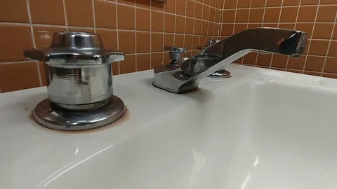 A chrome basic bathroom faucet dripping water close up Stock Footage 100096494