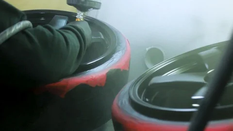 Chrome Black Alloy Wheels Being Spray Painted by a Mechanic at a Garage. Stock Footage 106678121