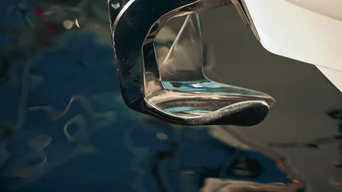 A chrome boat anchor with smooth curves, set against abstract blue and turquoise Stock Footage 322926749