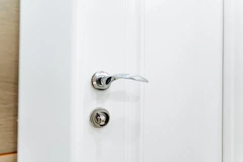 Chrome door hardware elements, silver handle, lock on the door to the room. Stock Photos