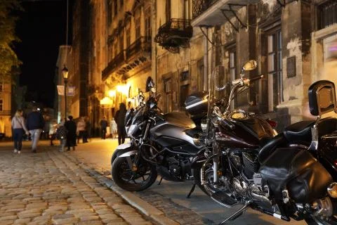 Chrome elements of stylish motorcycles in the lights of the ancient evening c Stock Photos