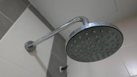 A chrome shower head with watermark attached to a curved pipe 库存影片 321634830