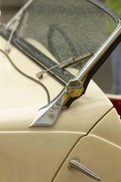 Chrome windshield ornament and hinge on cream vintage car hood Stock Photos
