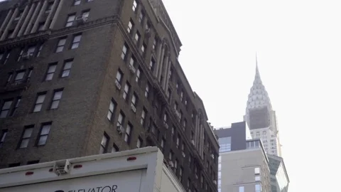Chrysler Building upward driving angle with truck in Midtown Manhattan NYC Stock Footage 70964238