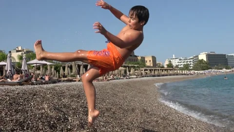 Chubby boy walking out of the sea and falling on the beach 2 Video stock 342736175