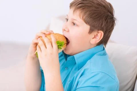 Chubby kid taking a bite off cheeseburger Foto stock