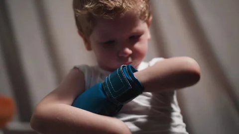 Chubby little boy fixes boxer glove on hand to punch bag Stock Footage 243310245