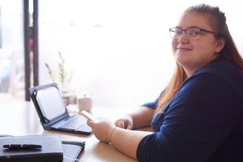 Chubby woman looking at camera while seated in a cafe Foto stock