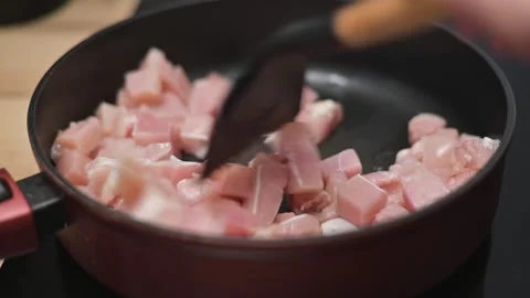 Chunks of chicken are placed in a frying pan as they cook over medium heat. A 库存影片 338298390