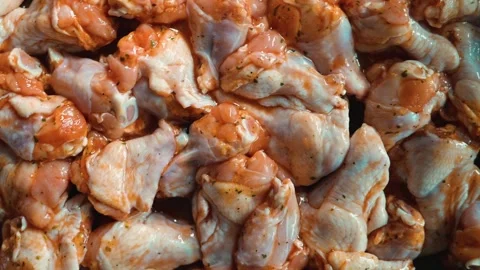 Chunks of chicken thighs are coated in a spice marination, preparing them for 動画素材 338290336