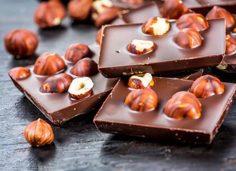 Chunks of dark chocolate with hazelnuts on table Stock Photos