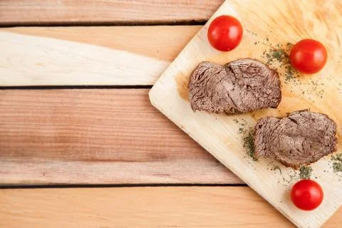 Chunks of deep-fried meat, steak on a wooden tray with spices and cherry toma Stock Photos
